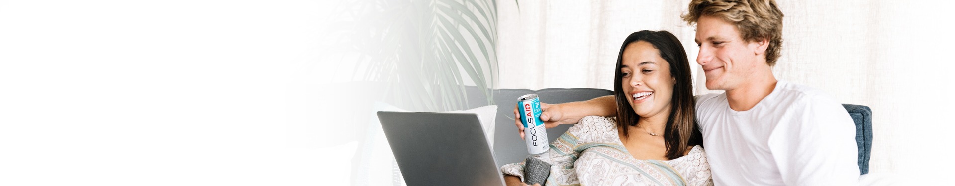 lifestyle header image of couple relaxing at home on their couch with a can of FOCUSAID, while perusing the internet together on their laptop