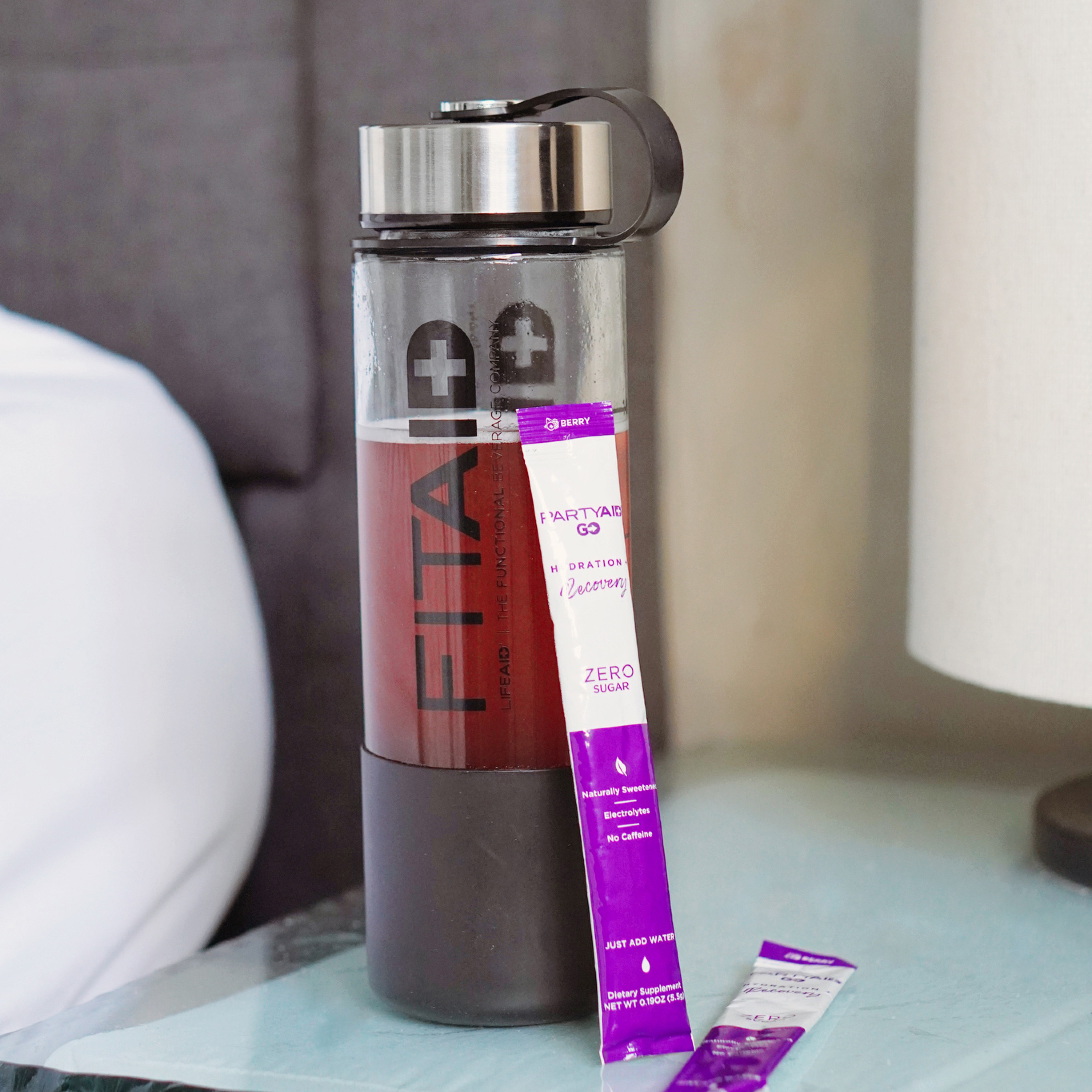 Two Partyaid GO sachets next to a FITAID water bottle.