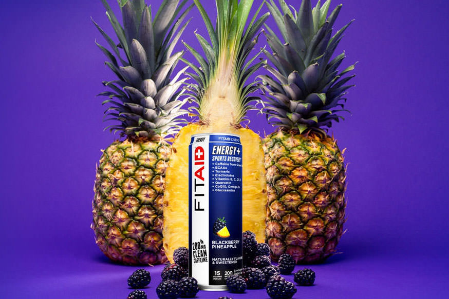A can of FITAID Energy Blackberry Pineapple surrounded by blackberry and pineapple.