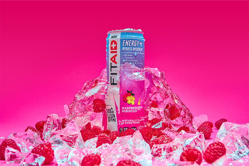 A can of FITAID Energy Raspberry Hibiscus surrounded by raspberry and ice cubes.