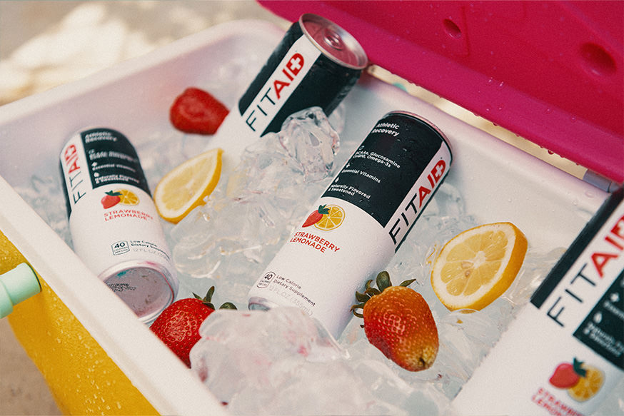 A can of FITAID Strawberry Lemonade surrounded by strawberries and lemons.