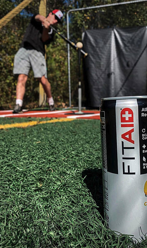 Brand ambassador in the background, hitting a golf ball, with a can of FITAID closer and focused to the camera