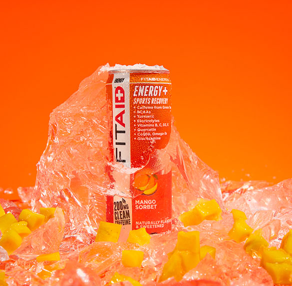 A can of FITAID Energy Mango Sorbet surrounded by mangoes and ice cubes.