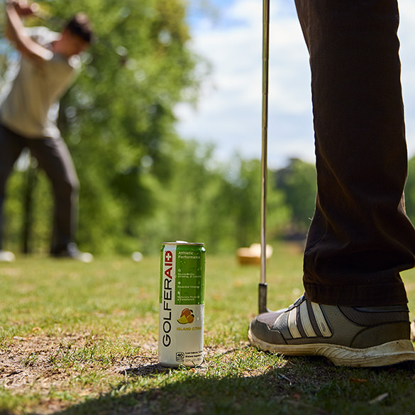 A golfer standing beside a can of GOLFERAID.